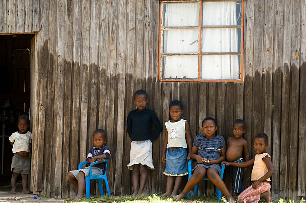 Soweto, South Africa - October 1, 2006: Group of black children in the township of Soweto relaxing in the shade. Soweto is famous for The Soweto Uprising, when  in 1976 mass protests erupted over the government's policy to enforce education in Afrikaans rather than English