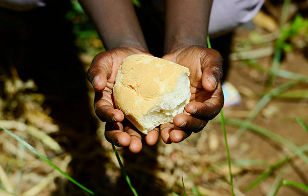 Starving Hunger Symbol. Black African girl holding bread as a malnutrition symbol. It is important to get food and life-saving aid to the world’s most vulnerable people and countries. Stop hunger in the world!